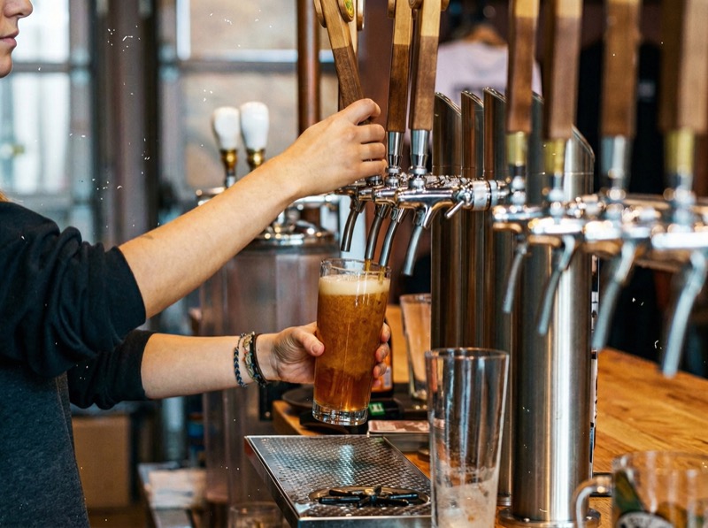 Bartender pouring craft beer from wooden tap handles